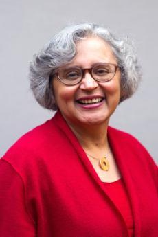 A headshot of a woman in a red suit jacket.